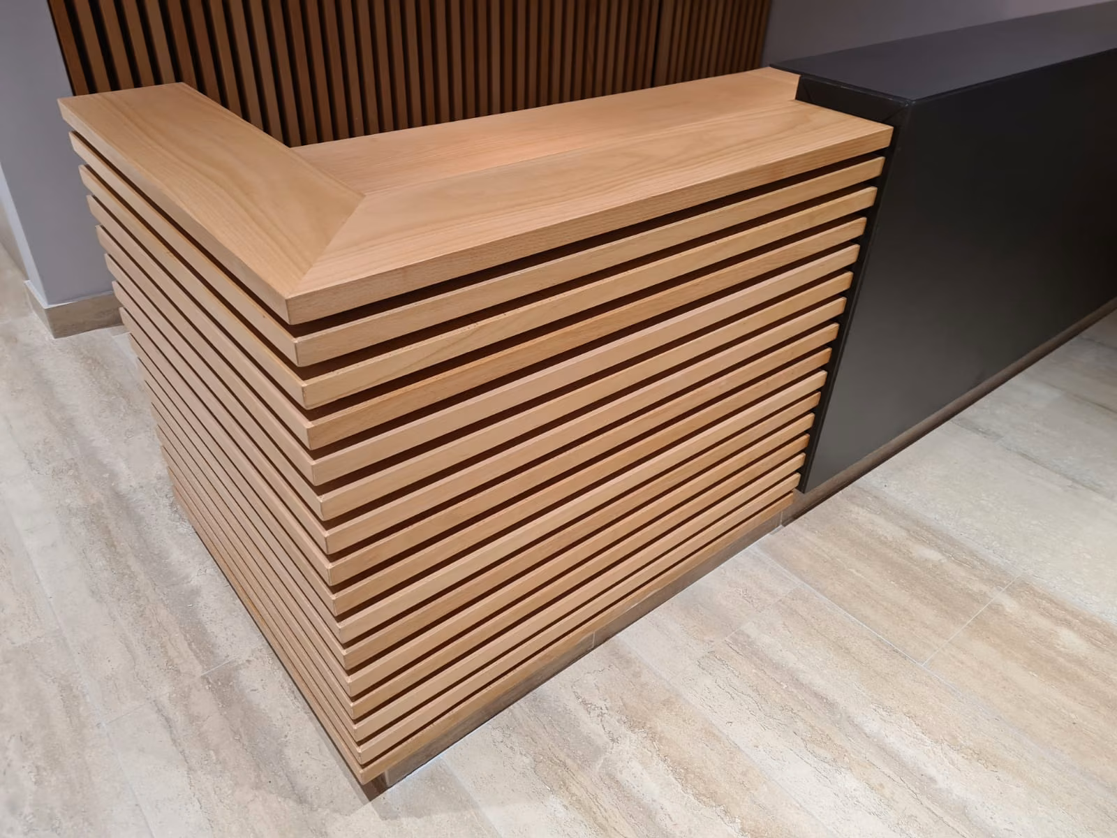 Mesón de recepción revestido en palillaje horizontal de madera, Family Office Providencia