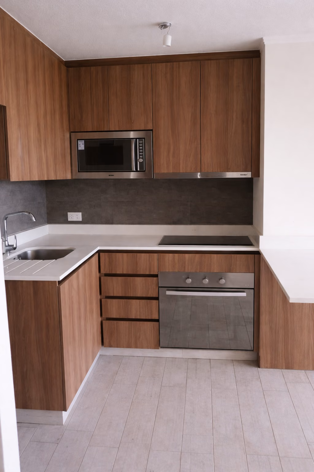 Cocina a medida con muebles de madera, horno y microondas empotrados