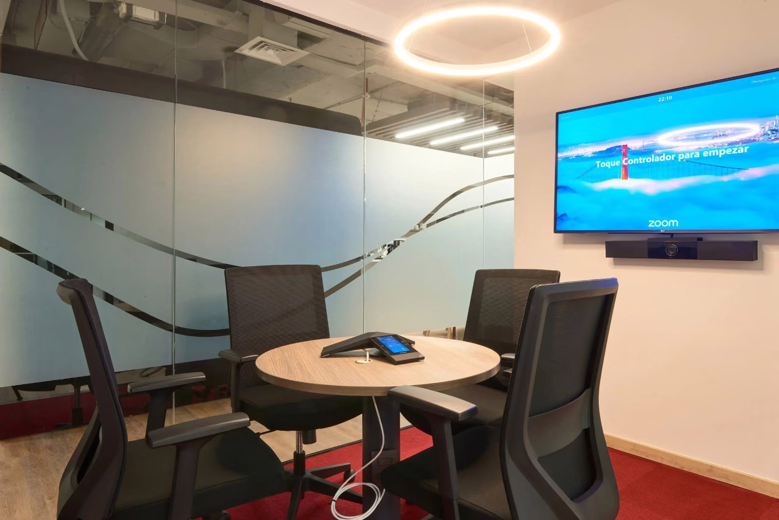 Sala de reunión con mesa circular y pantalla en el muro