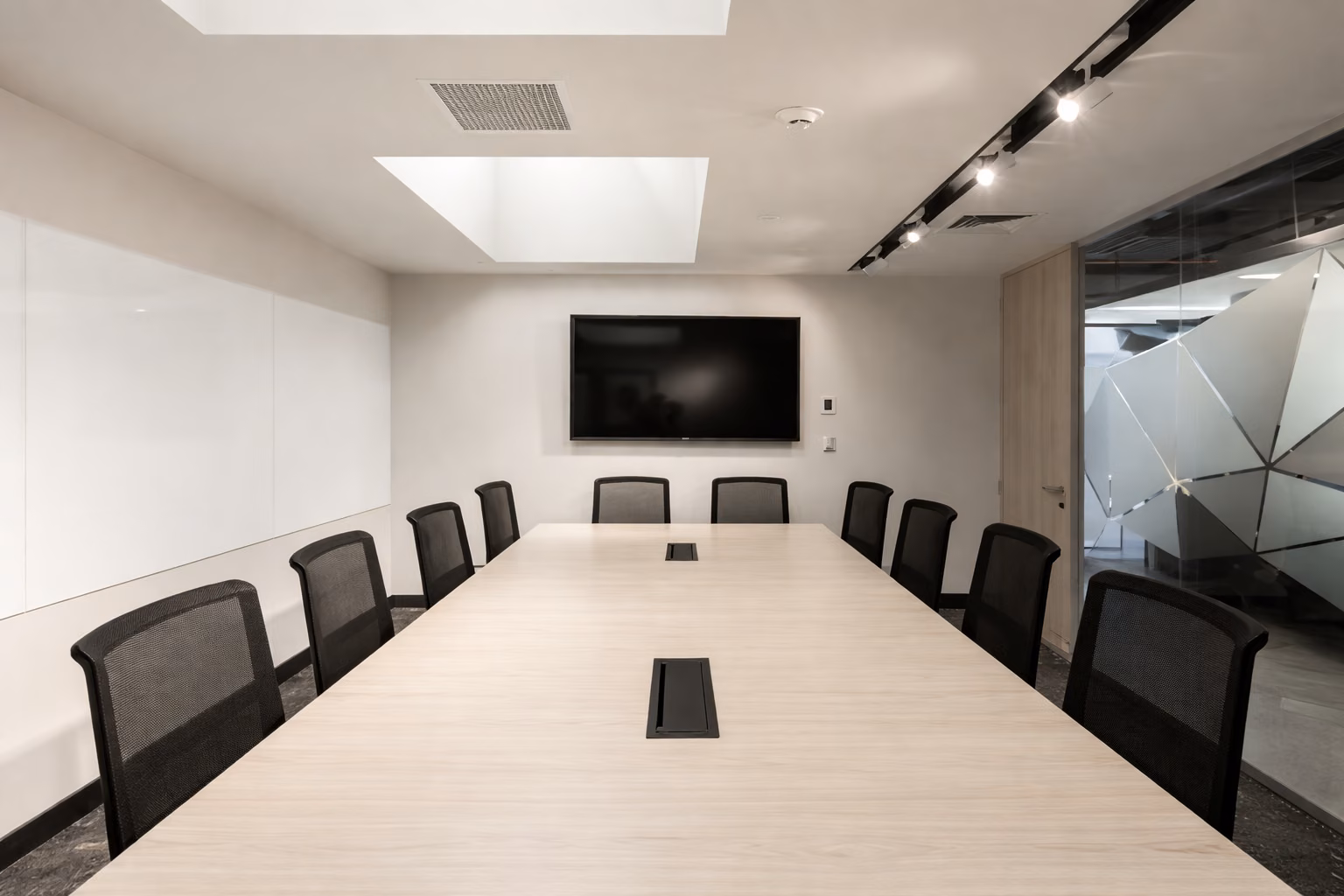 Sala de reunión con mesa larga y pantalla al fondo